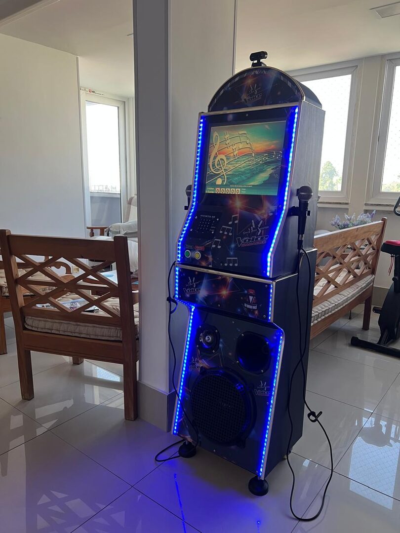 Máquina de karaokê DanSan instalada na sala de uma casa, com microfones e caixa de som integrada
